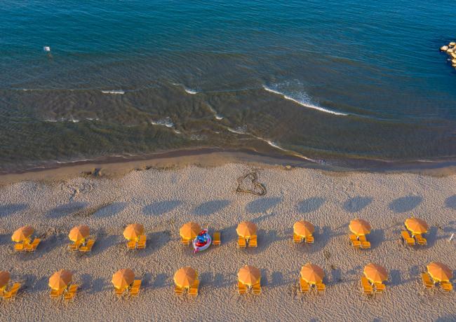 Spiaggia con ombrelloni arancioni e mare calmo.