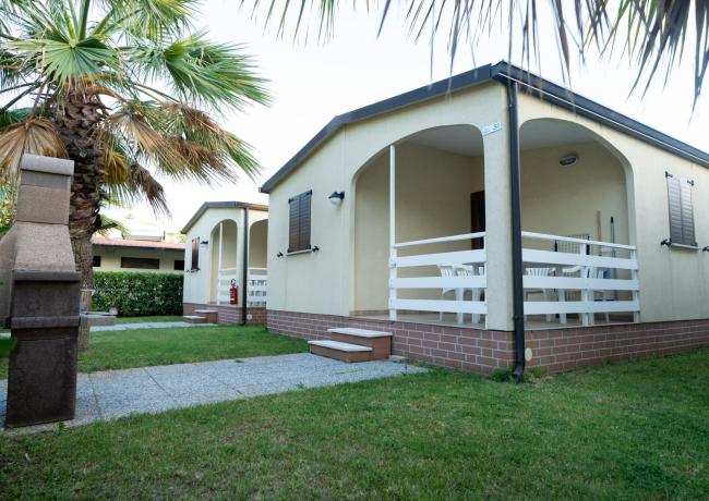 Bungalow con veranda e giardino, circondato da palme.