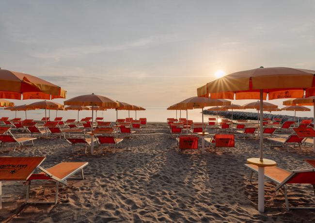 Spiaggia con lettini e ombrelloni al tramonto.