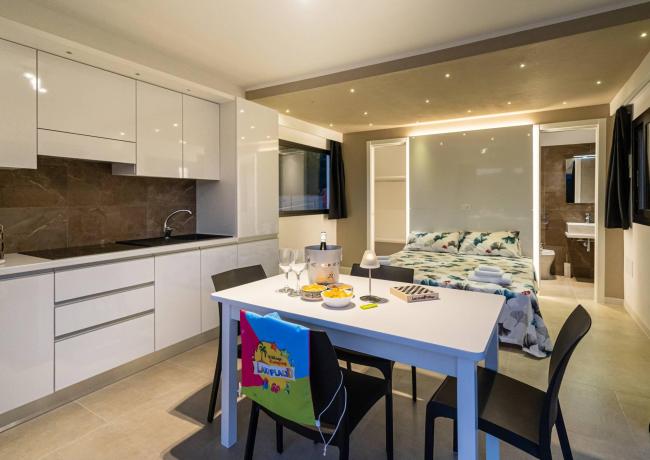 Moderno appartamento con cucina, tavolo da pranzo e letto matrimoniale.