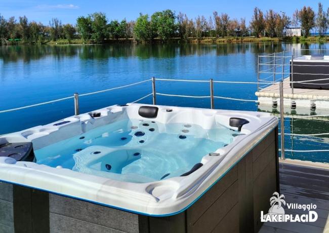 Vasca idromassaggio con vista lago e cielo blu.