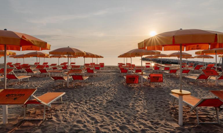 Spiaggia con lettini e ombrelloni al tramonto.