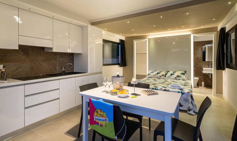Moderno appartamento con cucina, tavolo da pranzo e letto matrimoniale.